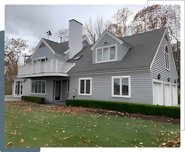 Gray house with balcony and green lawn.