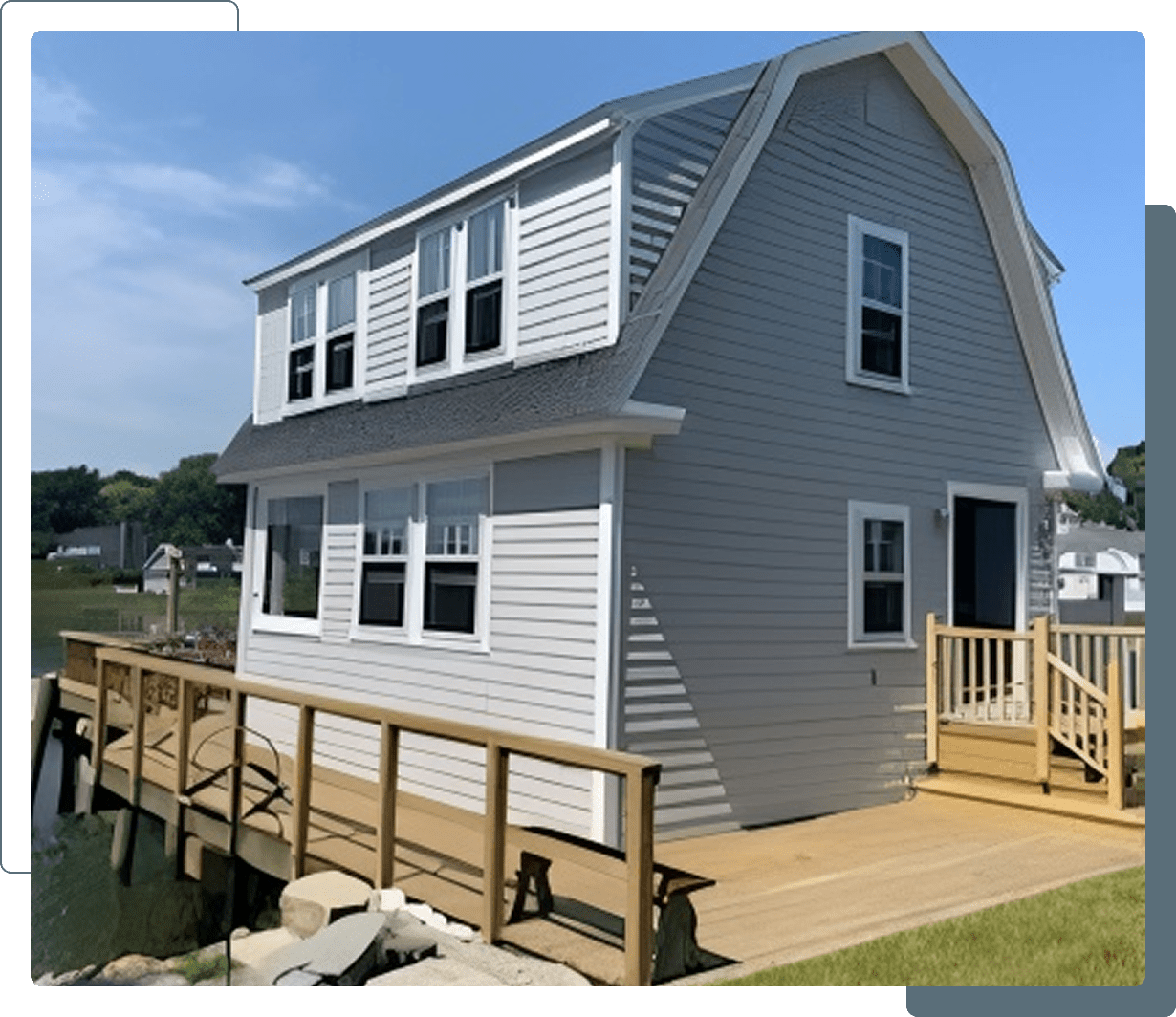 White house with wooden deck by water.