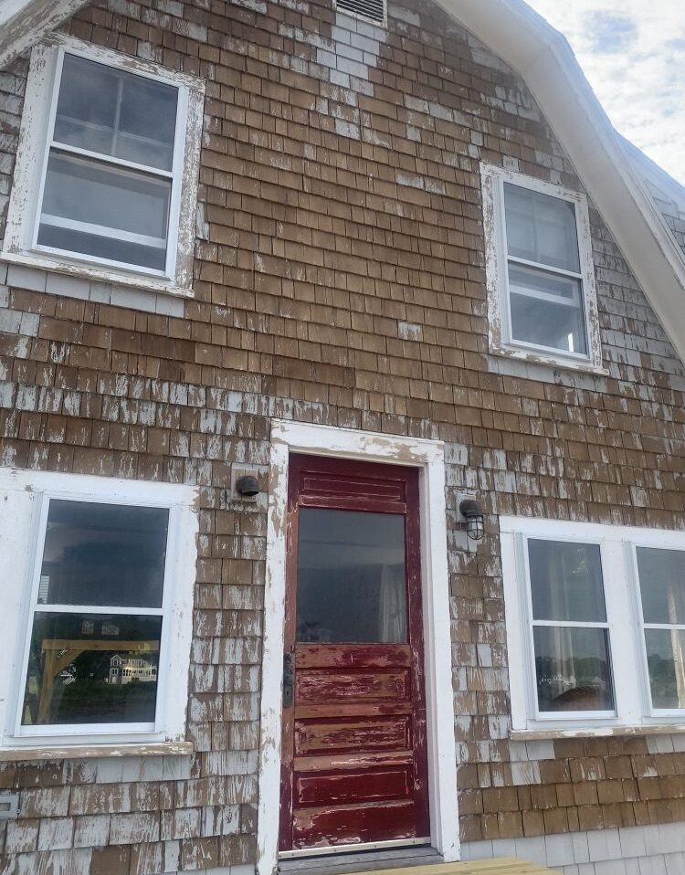 Aged house with red door and windows.